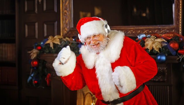 Santa Claus uses headphones to listen to music and dances in a great mood.