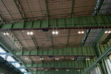 View under high ceiling of open interior space with huge steel truss, columns and beam structure...