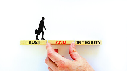 Trust and integrity symbol. Concept words Trust and integrity on wooden blocks. Businessman hand....