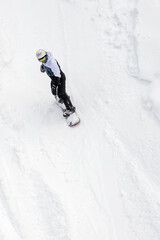 man on snowboard in equipment descends from snow-covered mountainside, active recreation in winter, extreme winter recreation