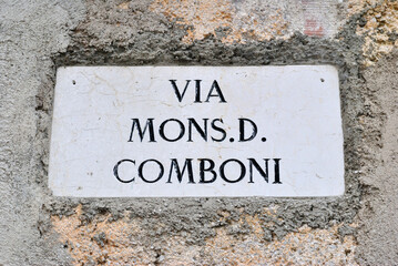 Fototapeta premium Close Up of Old Italian Stone Street Name Translated as 'Mister D Comboni Street' 