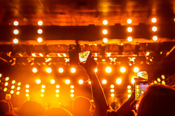 Mãos do público em contraluz em um show no teatro.