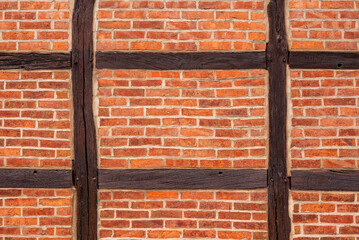 Background image showing a half-timbered wall made of brown wooden beams filled with red brick...