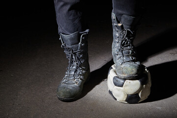Soccer ball and army boots. A soccer ball on a dark bon.