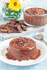 Chocolate dessert Panna Cotta on white plate, wooden board with chocolate on background vertical