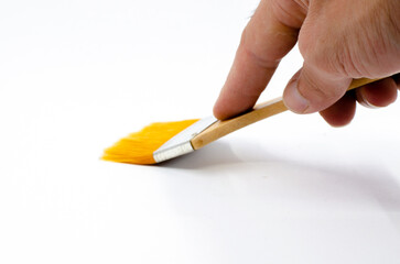 human hand holding a brush. Hand holding silk-tipped brush on white isolated background. Yellow paint brush.
