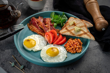 A full hot English breakfast with fried eggs, beans, tomatoes, toast, bacon and fresh salad.