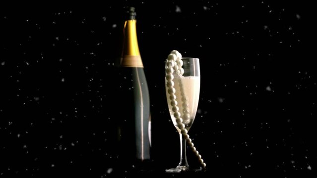 Animation of snow falling over glass of champagne