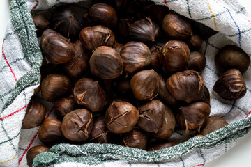 A small pile of hot roasted chestnuts wrapped in a kitchen towel