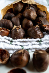 A handful of roasted chestnuts in a paper envelope on a kitchen towel