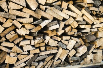 Chopped firewood stacked in a chaotic manner horizontally and vertically.  The concept of winterizing wood heating and heat.  Close-up, front view, pattern.