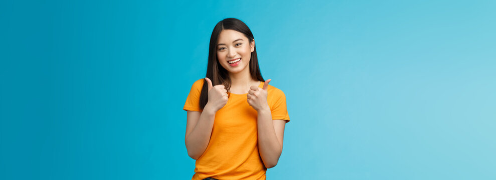 Supportive Cute Friendly Asian Girl Give Thumbs Up And Smiling, Cheering For You, Congratulate Nice Work, Approving Good Idea, Like Nice Outfit, Grinning Glad Accept Plan, Stand Blue Background