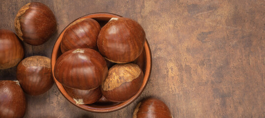 Edible chestnuts on dark rustic background.  Horse chestnuts top view. Flat lay, copy space.