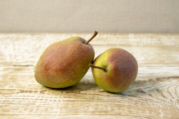Green yellow pears in brown wooden bowl on rough wooden background, top view.
