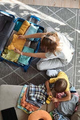 Mother and child are packing things in a suitcase together. Family relocation, flight from the...