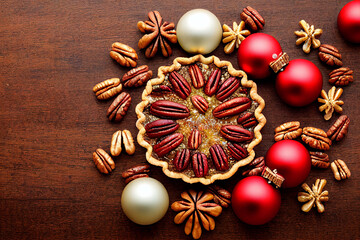 Pecan nut pie and christmas decorations laid flat on wooden background top view