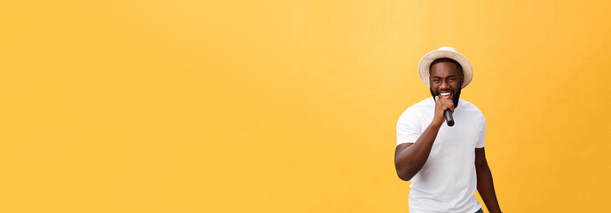 Fototapeta na wymiar young handsome african american boy singing emotional with microphone isolated on yellow background, in motion gesturing