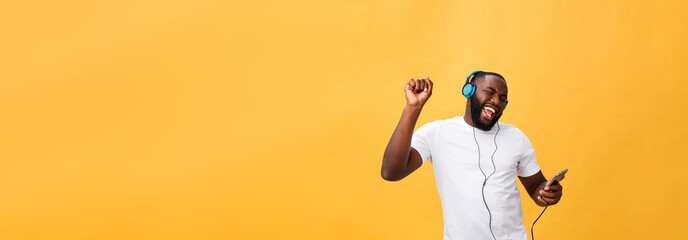 Fototapeta na wymiar African American man with headphones listen and dance with music. Isolated on yellow background