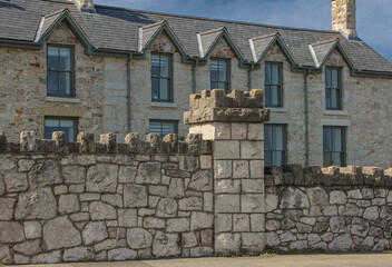 Pale coloured stone wall with a building behind