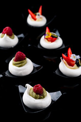 Sweet meringue cake with fresh raspberries On a black background