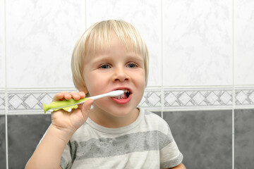 Little cute adorable blond caucasian baby toddler boy cleaning teeth tooth with toothbrush at bathroom at home in morning,evening. Funny child kid does daily hygiene health care