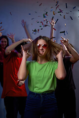 Girl near friends dance and have fun in confetti