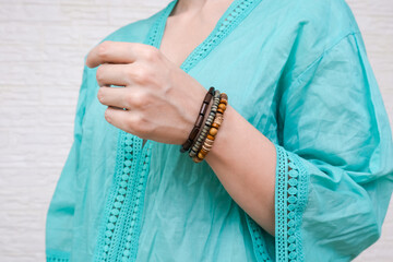 Unrecognized woman in ethnic clothes showing hand made bracelets with wooden beads on her hand