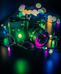 Naklejka na ściany i meble Old black photo camera with lens and led colorful lights with bokeh