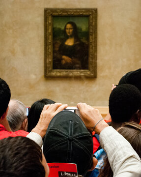 Paris, France; 07/11/2014: Crowd holding up a hall of the Louvre museum in Paris more concerned with taking photos than in observing Leonardo da Vinci's masterpiece, La Gioconda