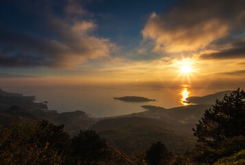 Budva bay from mountains and a colorful sunset sky with clouds at background
