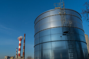 view of the boiler plant, the thermal power plant, two tall red and white pipes against the background of the sky, from which steam is coming out, the photo was taken in sunny weather