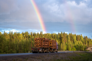 Asphalt road under the clouds. Top view of the road through the green summer forest. Rainbow over the forest in Karelia