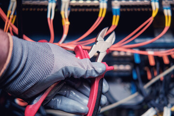 Wire cutters in the hands of a man at the server for data storage, close-up