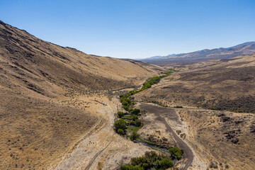 Aerial view of a road along a stream in an arid canyon in the northern Nevada desert.