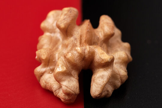 Close-up of a walnut fruit on a red-black background. Selective focus.