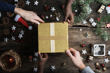 Mixed race family holding shiny golden christmas holiday gift box