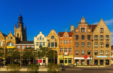 Fototapeta na wymiar Scenic view of summer cityscape of Roeselare overlooking belfry of Saint Michael Church rising above typical Flemish style townhouses on central Grote Markt square on sunny day, West Flanders, Belgium