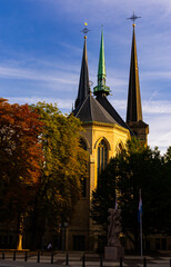 Classic view of Notre-Dame Cathedral in Luxembourg with high spires and flag of country