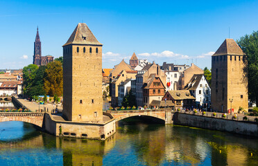 Fototapeta na wymiar Picturesque Strasbourg cityscape overlooking medieval arched Ponts Couverts and watchtowers seen from viewing platform of Barrage Vauban on sunny summer day, France