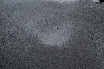 Obraz premium Background of wet and dark gray asphalt texture with puddle