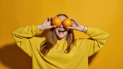 Joking female teenage cover her eyes with oranges