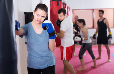 Female boxer is beating a boxing bag in the boxing hall.