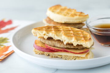 Waffle, apple and sausage sandwich served with maple syrup for dipping.