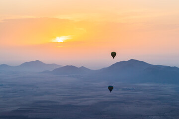 hot air balloon flying over the Moroccan desert and the atlas mountains at sunrise