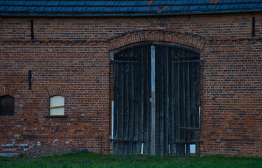 Fototapeta na wymiar old black wooden doors of brick barn 