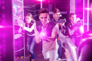 Obraz na płótnie Canvas Portrait of young man with laser gun having fun on dark laser tag arena..
