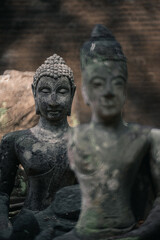 Fototapeta premium Ancient old ruin Head of Buddha statue carved from sandstone was destroyed and abandoned left in the Wat U Mong Temple.