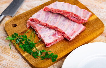 Uncooked pork ribs rack ready for cooking on wooden cutting board