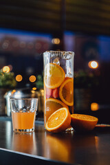 lemonade from orange and berries in two modern glasses in the form of a can and a carafe on a table.