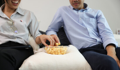 A couple eat snake popcorn , Young couple relaxation at home watching a movie and eating popcorn , enjoy and happy living at home concept